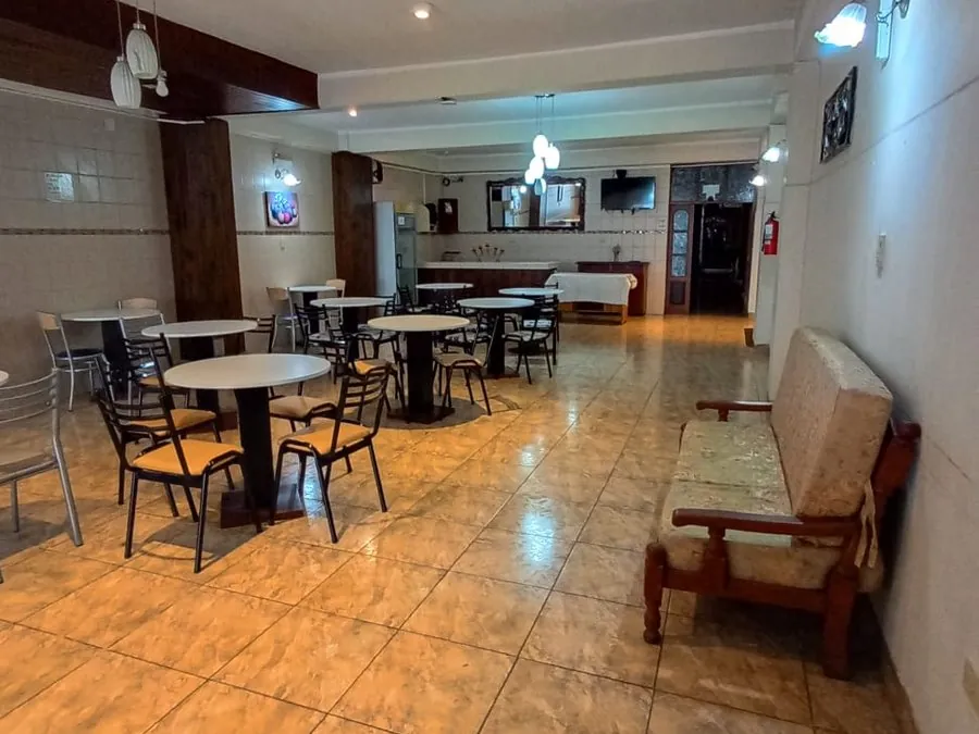 Salón desayunador amplio con mesas redondas blancas y piso cerámico